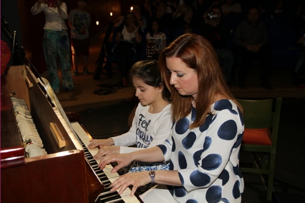 teacher playing piano with a girl